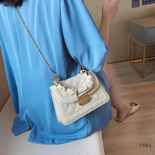 Bolsa blanca con cadena metálica usada al hombro para estilo casual chic