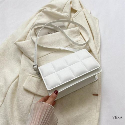 Bolsa bandolera blanca acolchada de Vera sobre fondo beige
