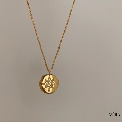 Collar dorado con estrella sobre blusa clara